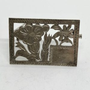 Broche argent en plaque, motifs de fleurs découpées et cartouche.