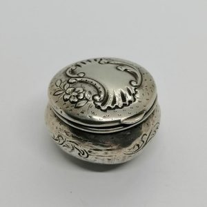 Boîte à pilules argent, décor coquille et fleur, sur fond guilloché et martelé,1900.